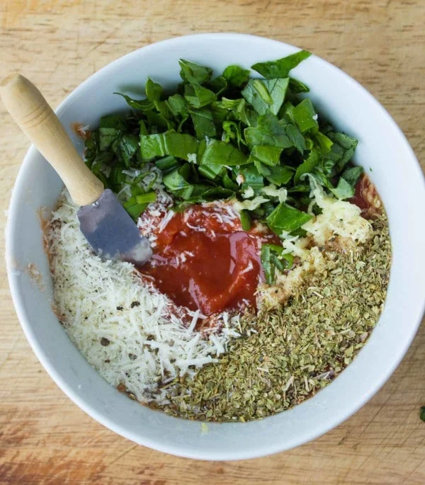 Pizza Sauce ingredients in a small bowl: curshed tomatoes, oregano, basil, garlic, parmesan cheese