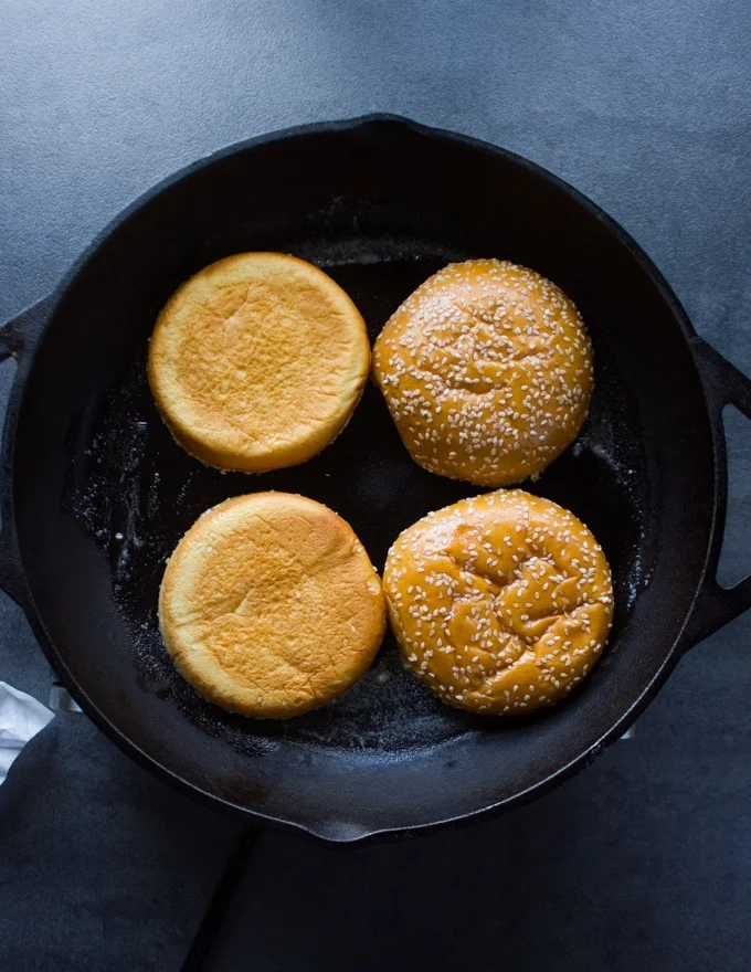 A skillet with brioche buns placed cut side down for toasting
