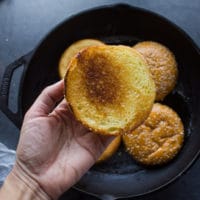 A hand holding the toasted brioche bun showing the golden crust