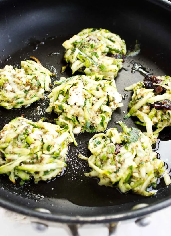 gluten-free zucchini fritters with feta and cranberries being fried in a pan
