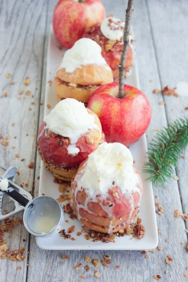 Baked Apples with Granola Crunch filling and vanilla ice cream served on a white rectangular plate
