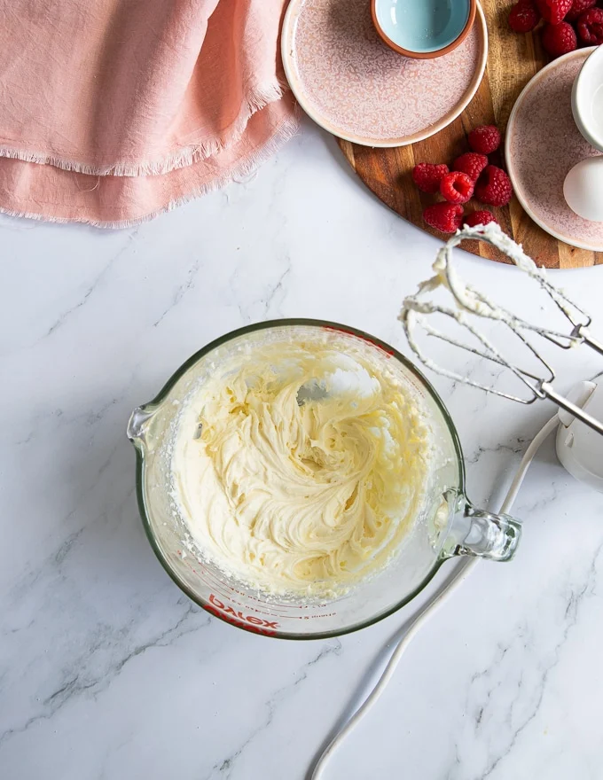 Smooth and fluffy beaten cream cheese and sugar in a bowl to make cheesecakes