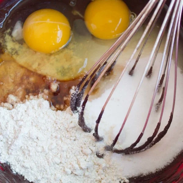all ingredients for gluten free brownies recipe in a bowl with a whisk