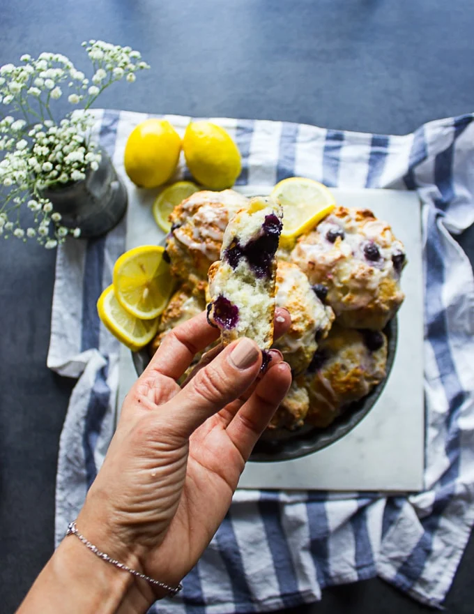 A hand holding a drop biscuit bitten to show the inside texture of the biscuit