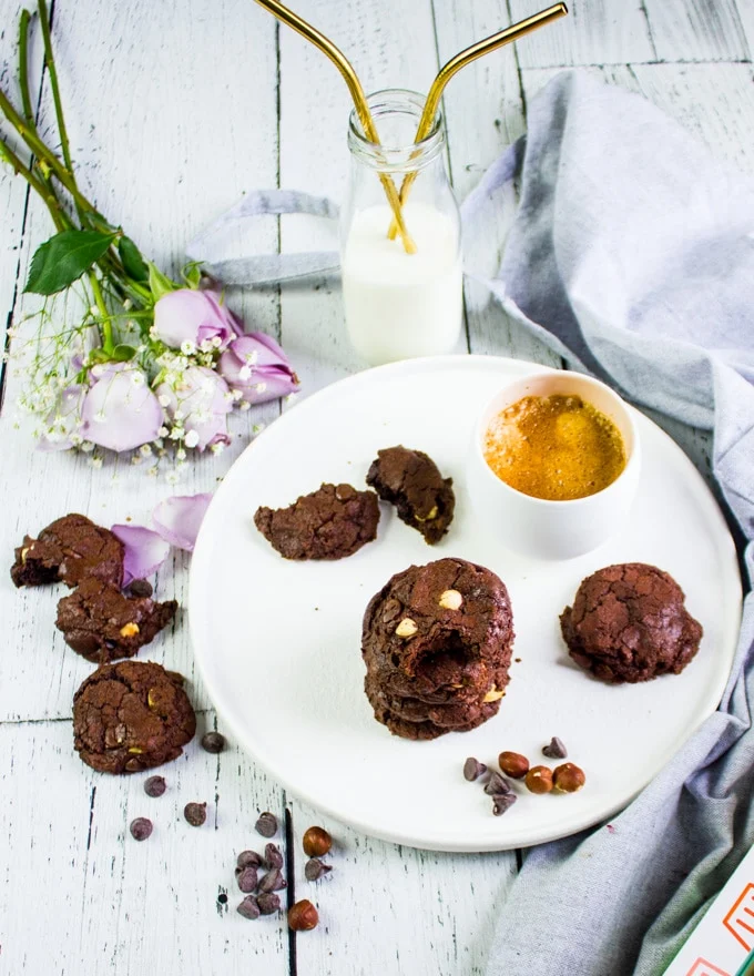 A plate of brownie cookies with a glass of milk and coffee