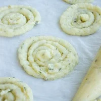Leftover Mashed Potatoes mixture being piped onto a lined baking tray to make crisps
