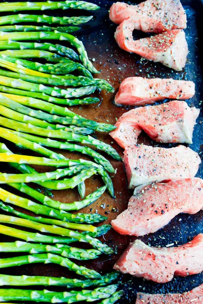 salmon and asparagus raw being roasted to make the nicoise salad.