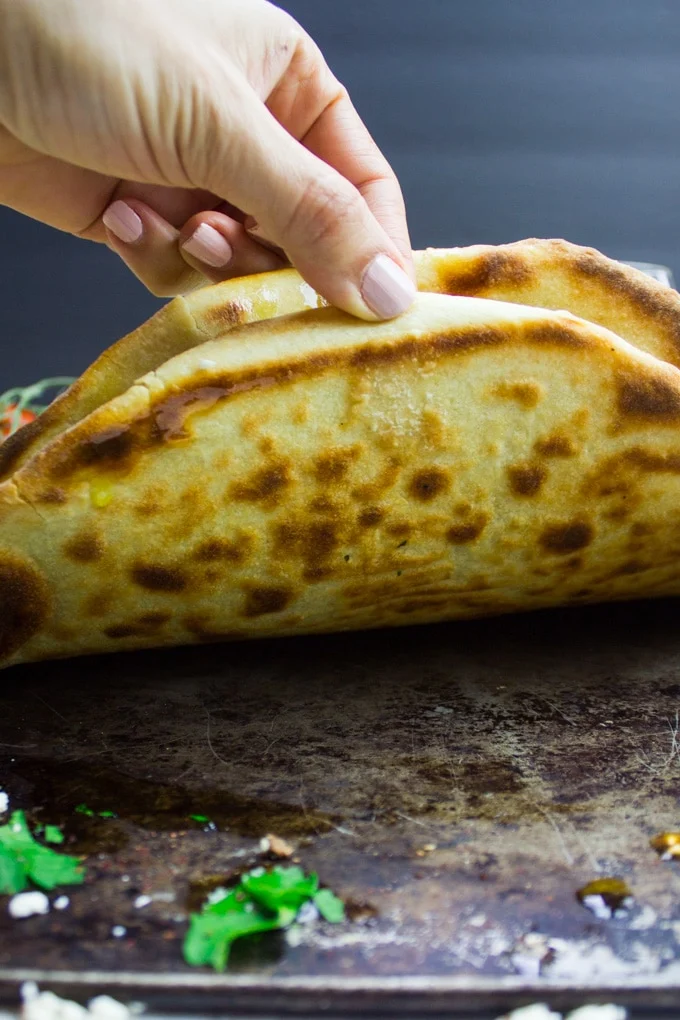 A hand holding a pizza showing the bottom crust golden and cooked