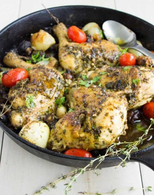 Garlic Herb Roast Chicken served in a black skillet with some blistered tomatoes and fresh herbs