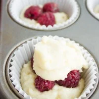 close-up of a unbaked muffins with fresh raspberries peaking out of the batter.