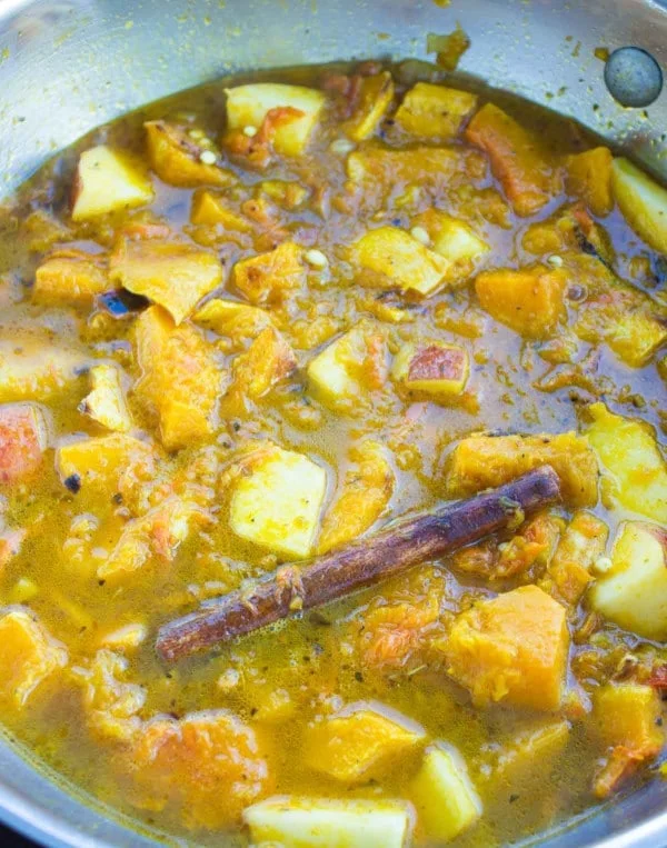 mediterranean soup simmering in a pan showing the ingredients and cinnamon stick