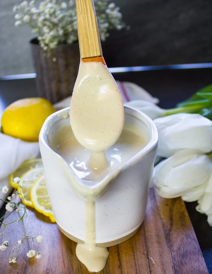 A spoon drizzling the tahini sauce showing the thickness of the tahini sauce