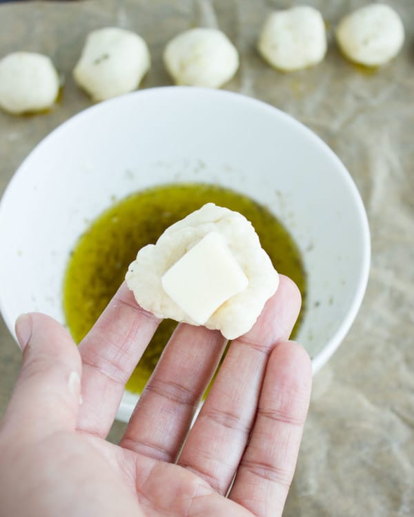 a cube of mozzarella cheese being wrapped in pizza dough