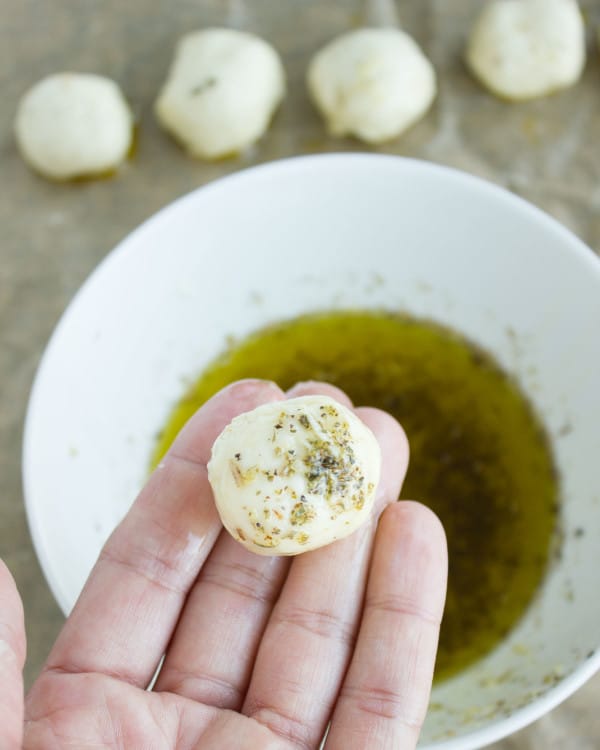 unbaked Pizza Popcorn Bites being dipped into seasoned olive oil