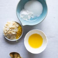 ingredients for the lemon toppings crunchy toping for raspberry muffins rercipe including a bowl of butter, bowl of sugar, lemon zest, sliced almonds and a spoon