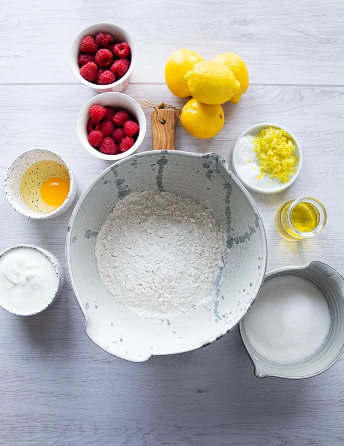 ingredients for the raspberry muffins recipe including flour, baking powder, sugar, lemon zest, oil, egg, yogurt, raspberries