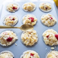 A spoon adding the crunch tropping over the raspberry muffins recipe right before baking