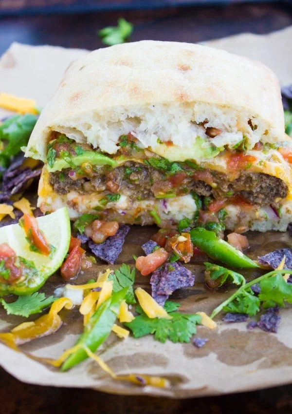 A finished burger cut in half showing the juicy burger on the inside and all the fajita toppings layered