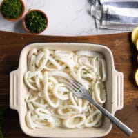 Squid rings in a buttermilk or milk mixture soaking to tenderize before coating and frying