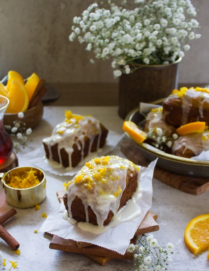 A set of two carrot cake glazed with orange glaze and topped with orange zest.