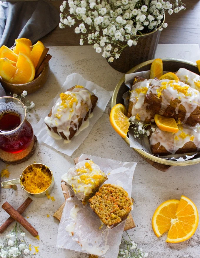 An orange carrot cake cut in half on a plate