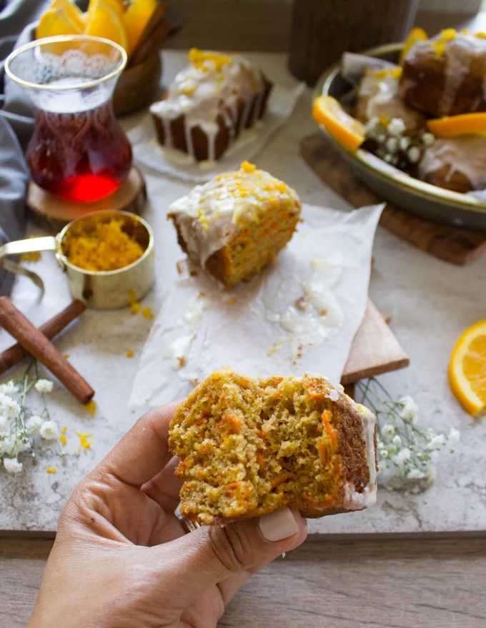 A hand holding a carrot cake bit and showing the inside texture