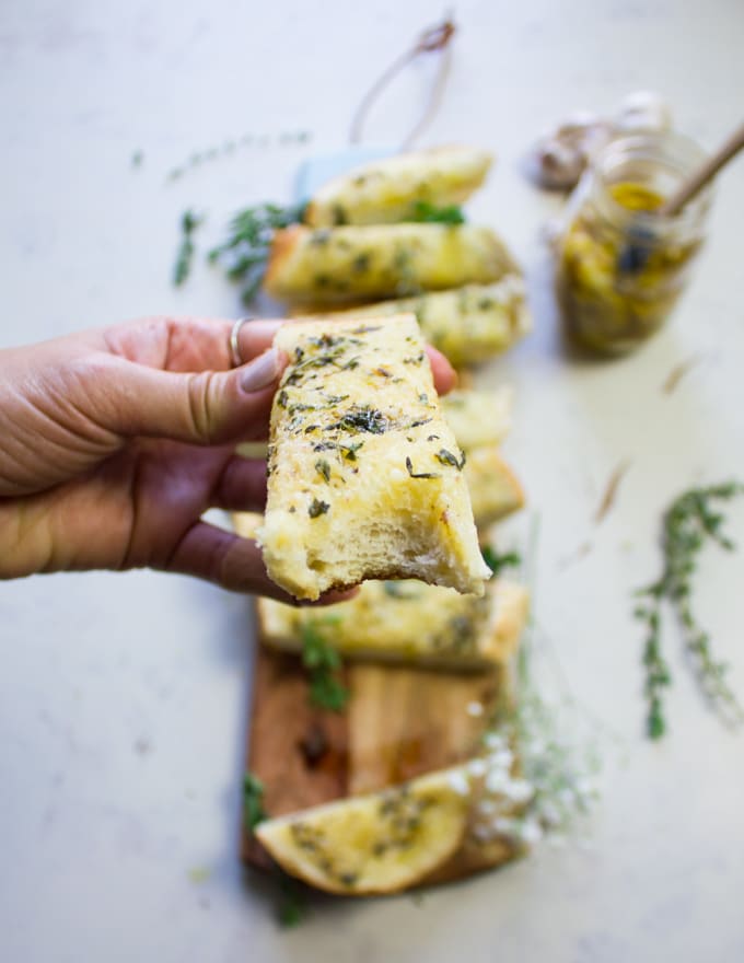 A hand holding a piece of garlic bread bitten