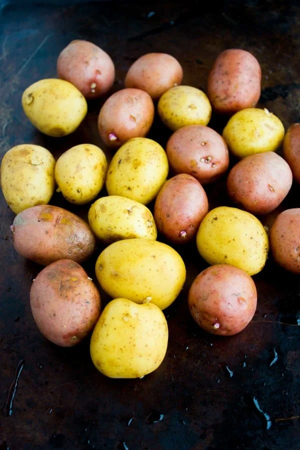 washed red and yellow potatoes arranged on a black baking sheet