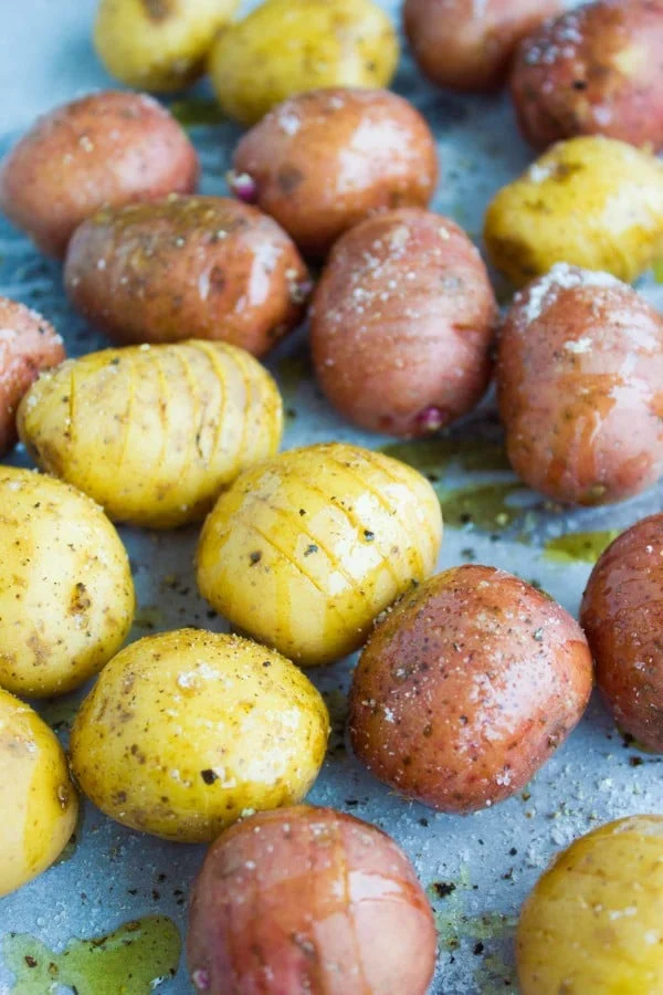 seasoned and sliced potatoes on a sheet pan ready for baking