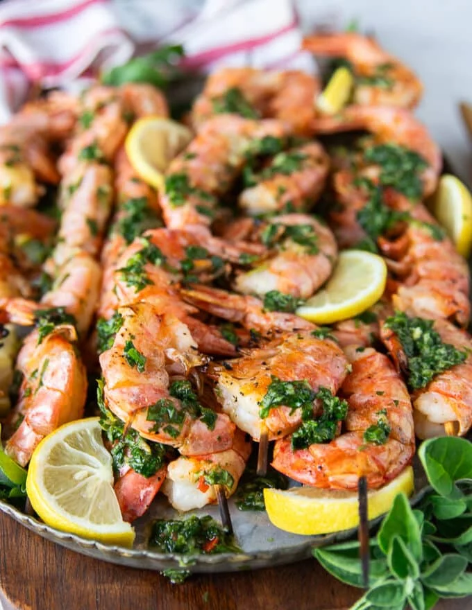 Close up of a grilled shrimp skewer dressed up with herbs and lemon