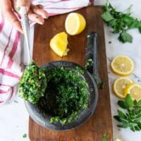 A hand holding the chimichurri sauce ready for the shrimp