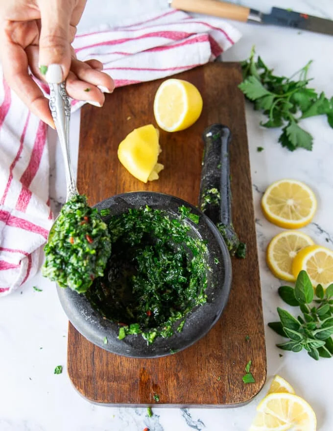 A hand holding the chimichurri sauce ready for the shrimp
