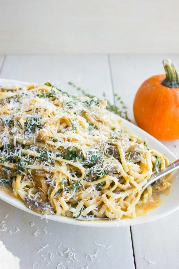 a big plate of Kale Mushroom Pumpkin Alfredo Pasta with parmesan grated on top
