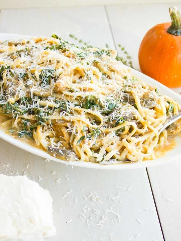 a plate of Kale Mushroom Pumpkin Alfredo Pasta with grated parmesan on top