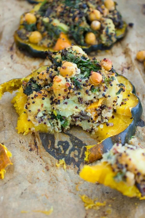 a half eaten acorn squash ring topped with quinoa kale stuffing