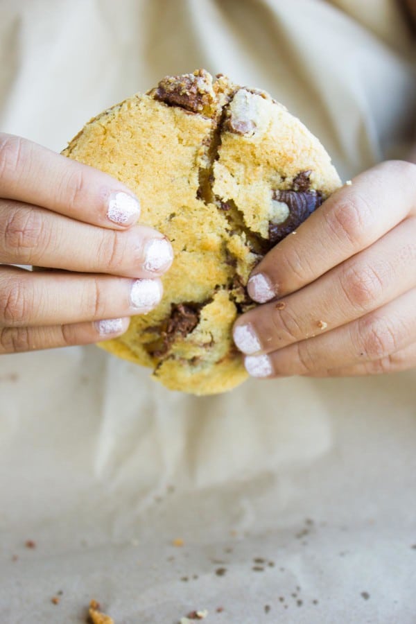 two hands holding a big Nutella-Stuffed Chocolate Chip Cookie