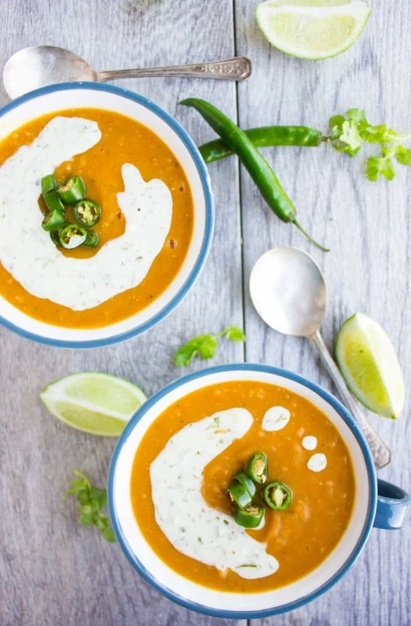two bowl of healthy lentil soup with red lentils quinoa and sweet potatoes served with a sour cream drizzle