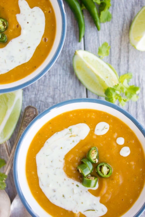 two bowl of healthy lentil soup with red lentils quinoa and sweet potatoes served with a sour cream drizzle