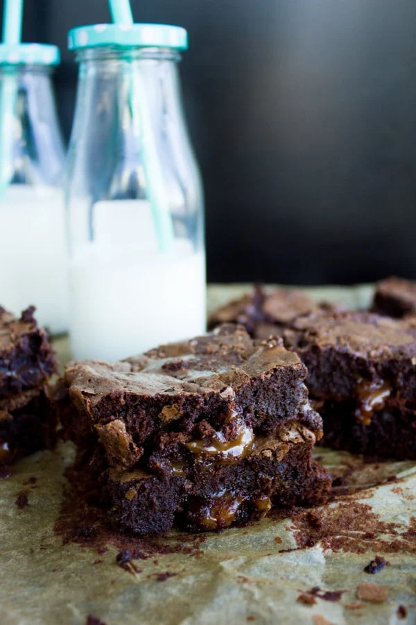 Side-view of two stacked chocolate brownies with caramel oozing out of the center