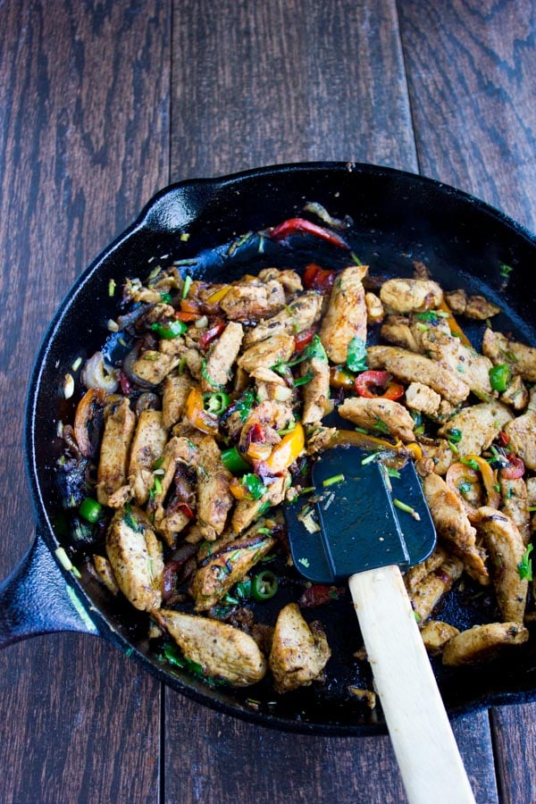 chicken fajitas being prepared in a black skillet