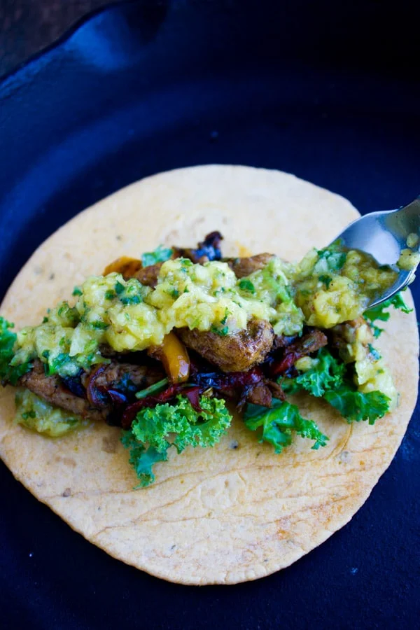 Chicken Fajitas on a tortilla being topped with Mango Pineapple Salsa