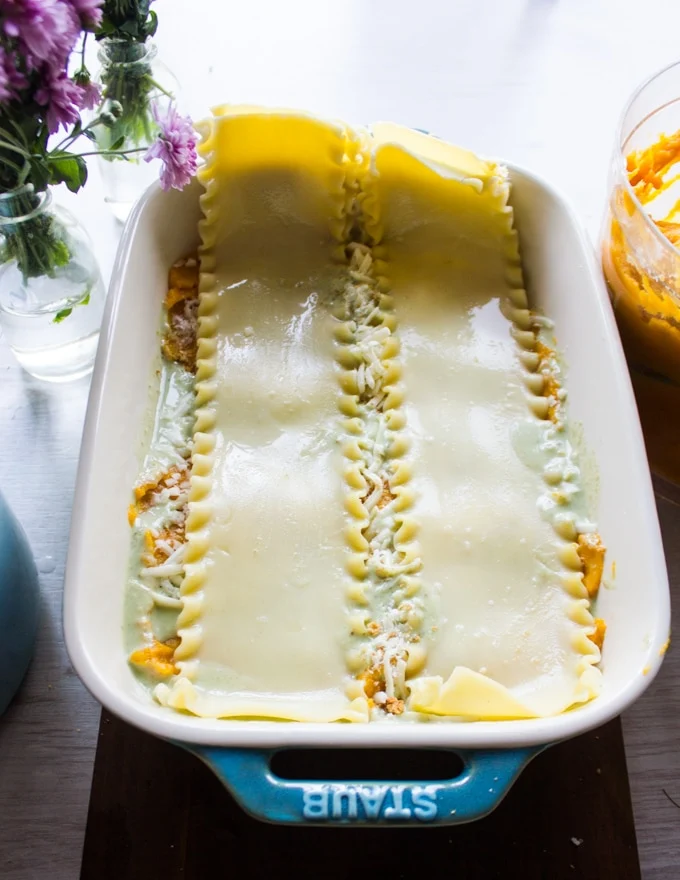 Assmebling the lasagna with layers of basil sauce, butternut squash and lasagna sheets.