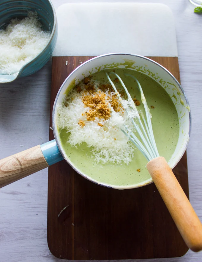 Place the basil béchamel back in the pot to finish the sauce. Parmesan cheese, and amaretti cookies on top to whisk in the sauce.