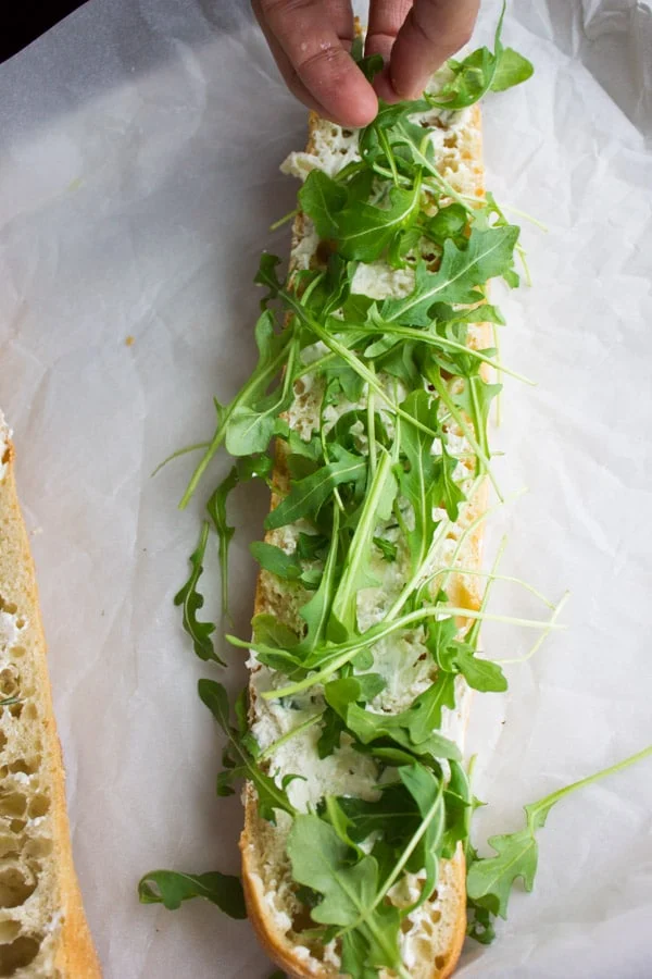 half a baguette sliced open with some arugula on top