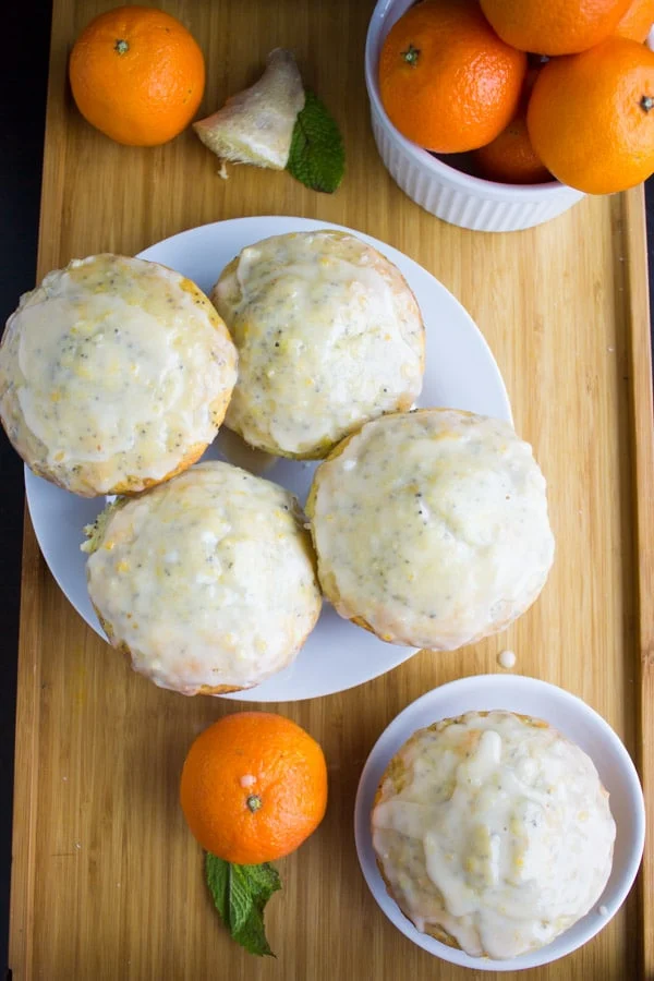 One-bowl Ginger Clementine Lemon Poppy Seed Muffins on a white plate with some clementines on the side
