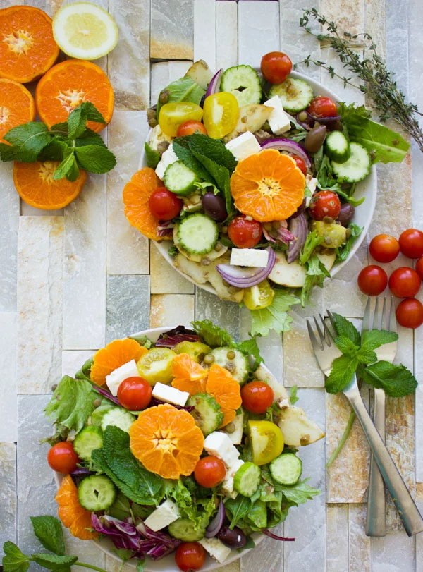two bowls of Orange Lentil Greek Salad with feta cheese and cocktail tomatoes