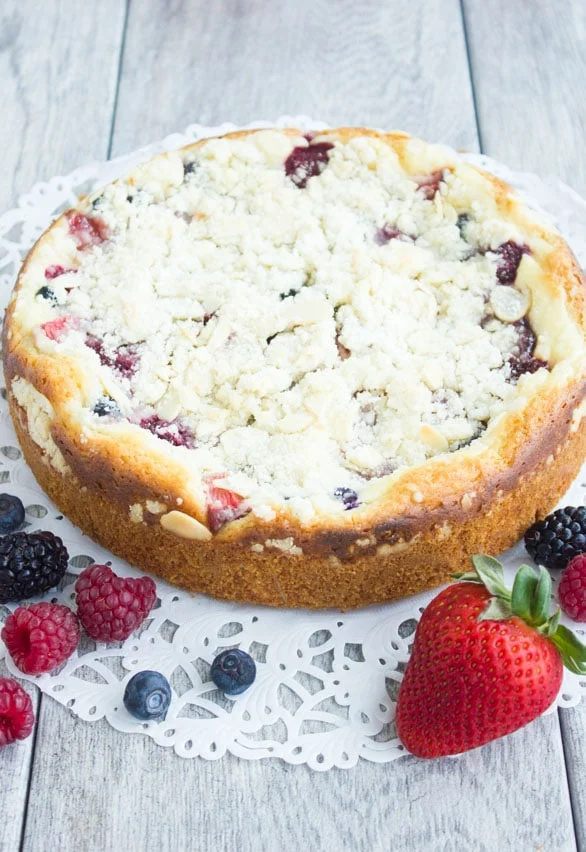 freshly baked Raspberry Cake with buttery streusel topping, dusted with powdered sugar placed on a cake doily ready to be served