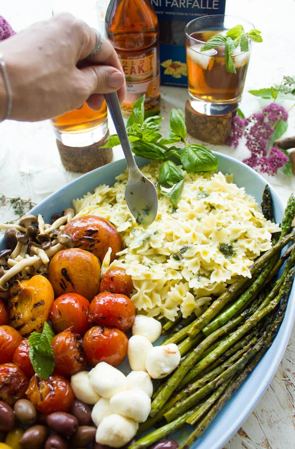 Sweet tea dressing being drizzled on top of a Summer Pasta Salad in an oval bowl.