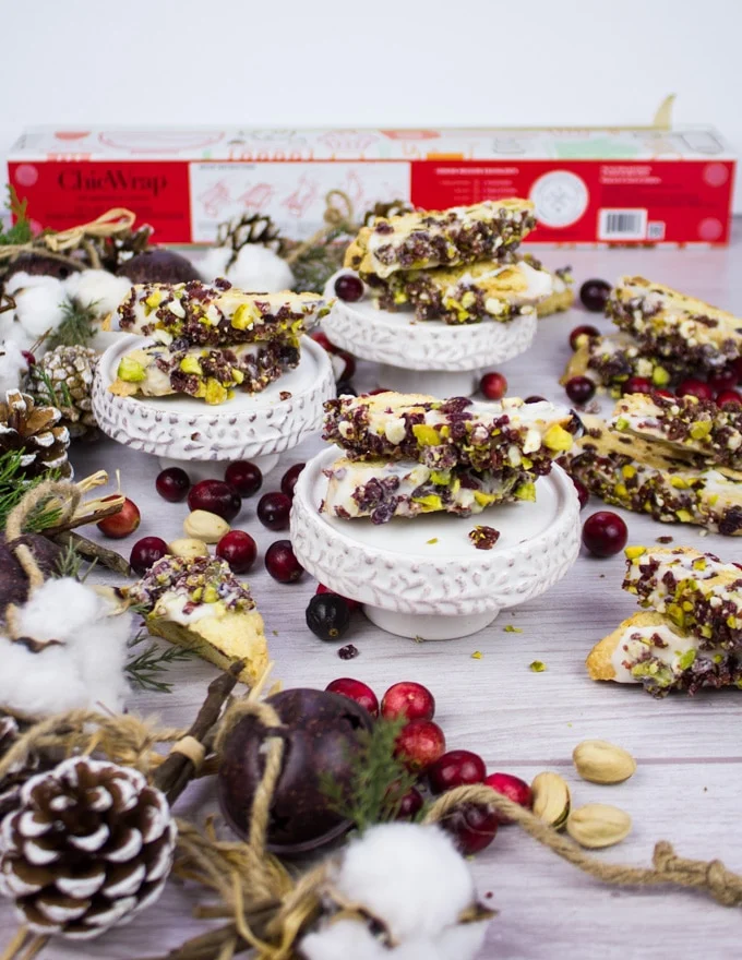 A collection of the biscotti cookies with crnaberry pistachip biscotti surrounded by holiday wreath