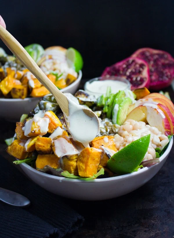 easy Tahini Dressing being drizzled on top of Lentil Fall Harvest Buddha Bowl.